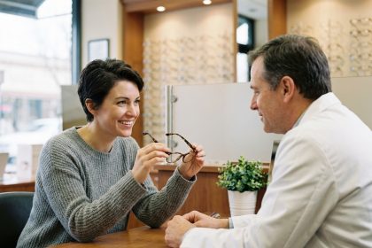 Une femme discute avec un opticien de quartier dans une boutique chaleureuse pour choisir ses lunettes